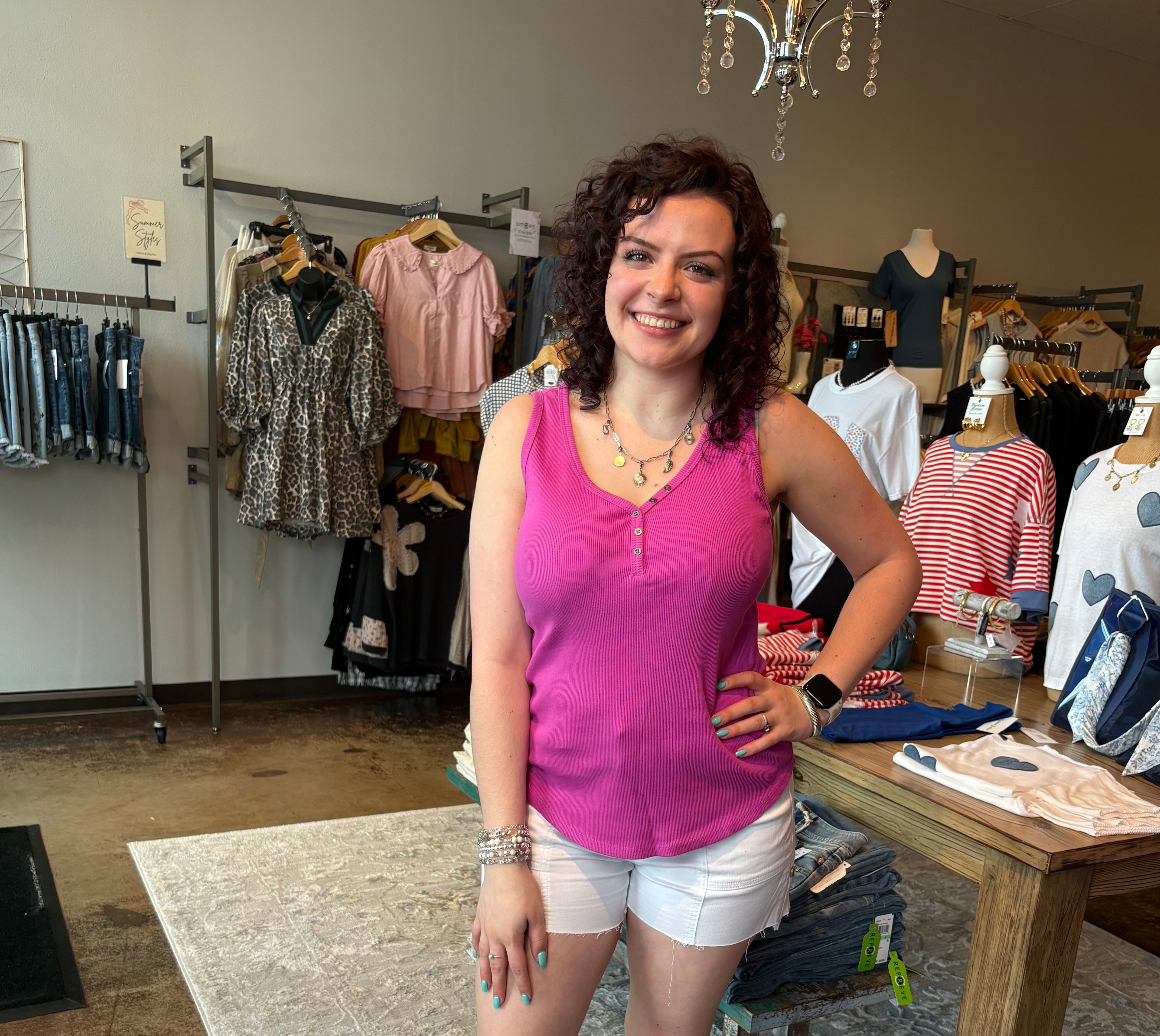 Woman in a pink top and white shorts standing in a clothing store.
