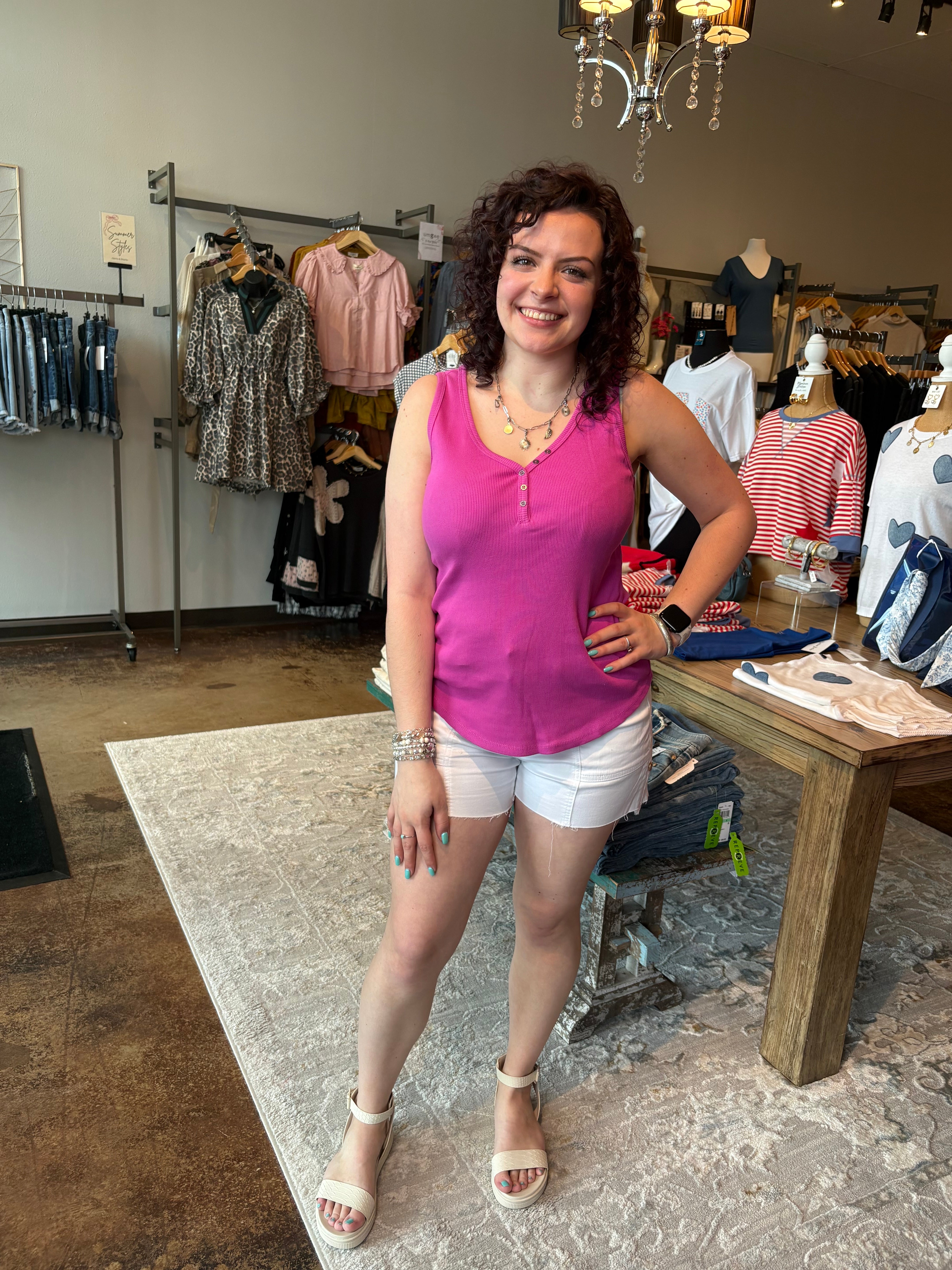 Woman in a pink top and white shorts standing in a clothing store.