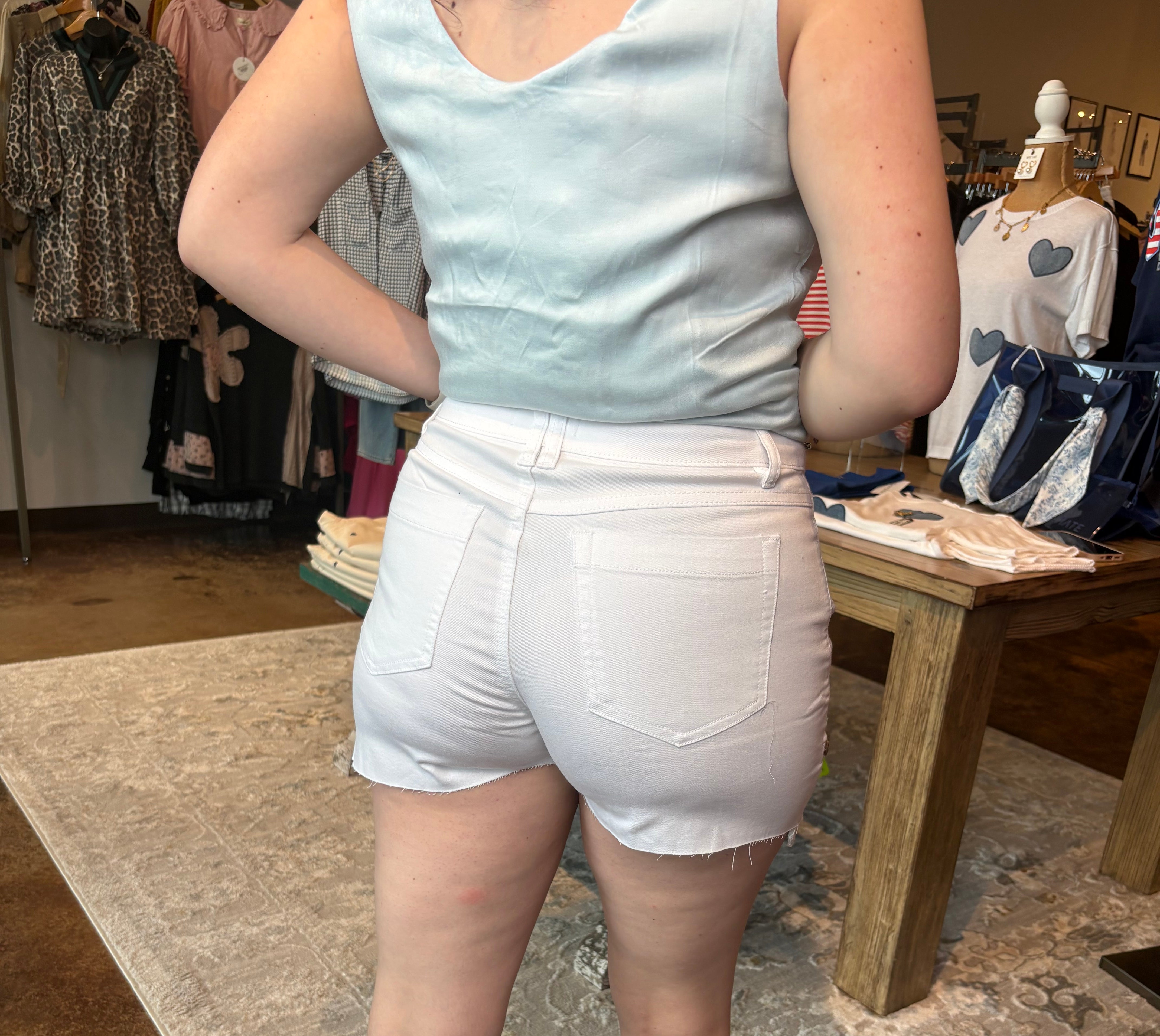 Person wearing a light blue sleeveless top and white shorts in a store setting.
