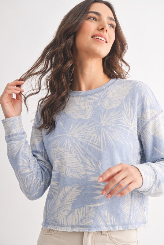 Model wearing dusty blue tropical print French terry crewneck sweatshirt, close-up front view