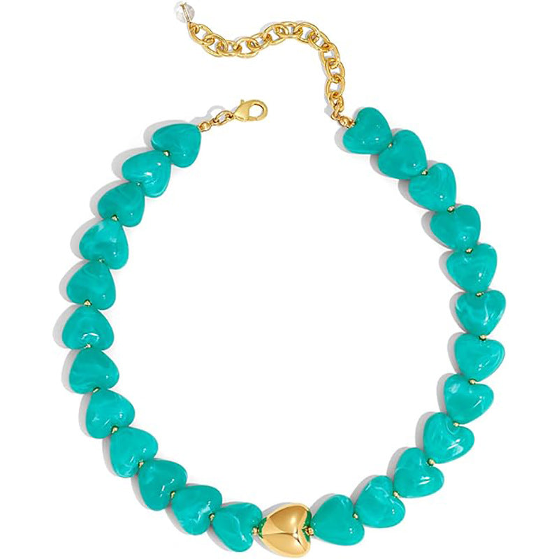 A heart-shaped beaded necklace with turquoise-colored stones and gold-tone metal accents, including a central gold heart and chain clasp, shown on a plain white background.