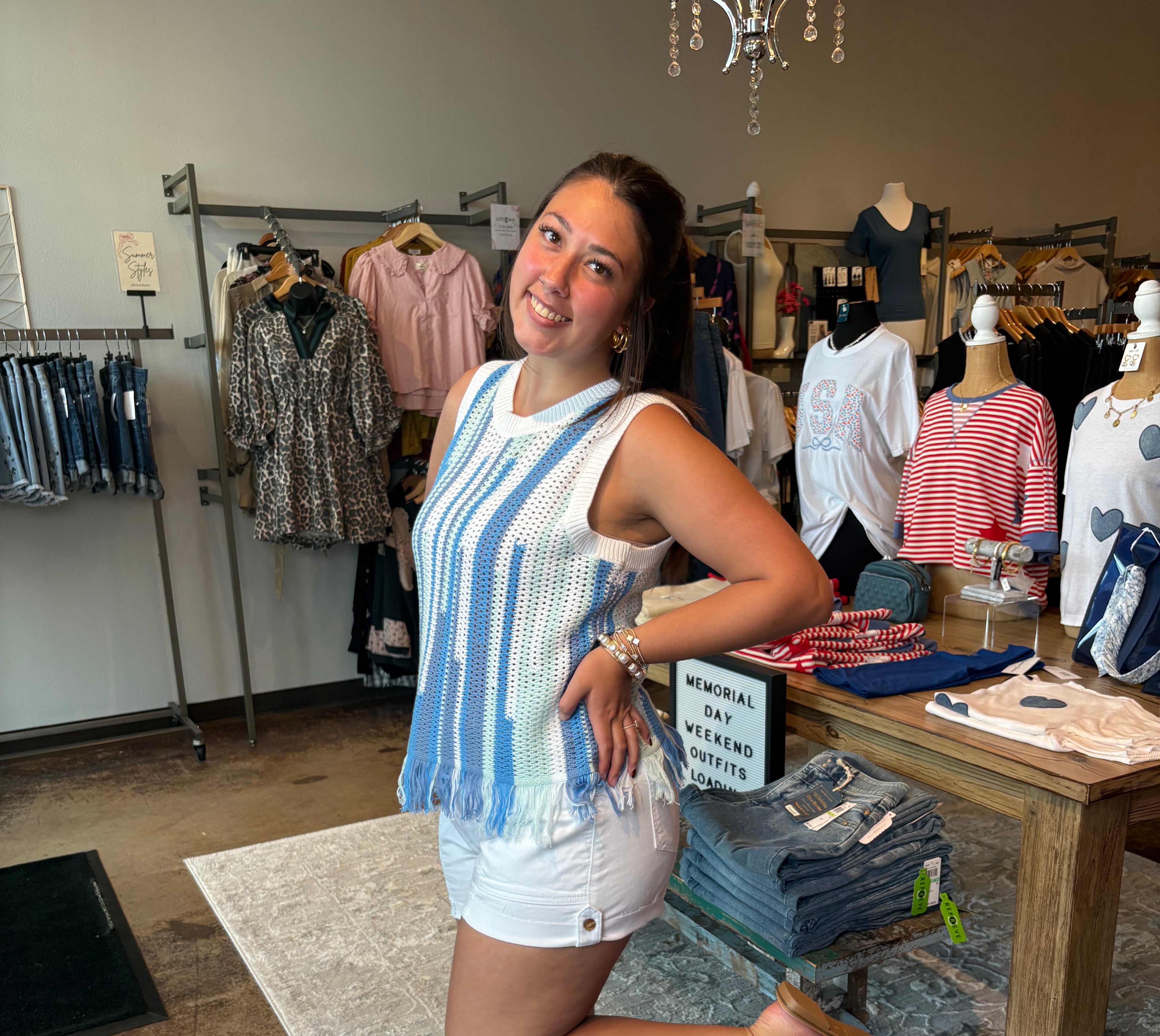 Woman wearing a crocheted sleeveless top. Blue and light green stripes on the tank