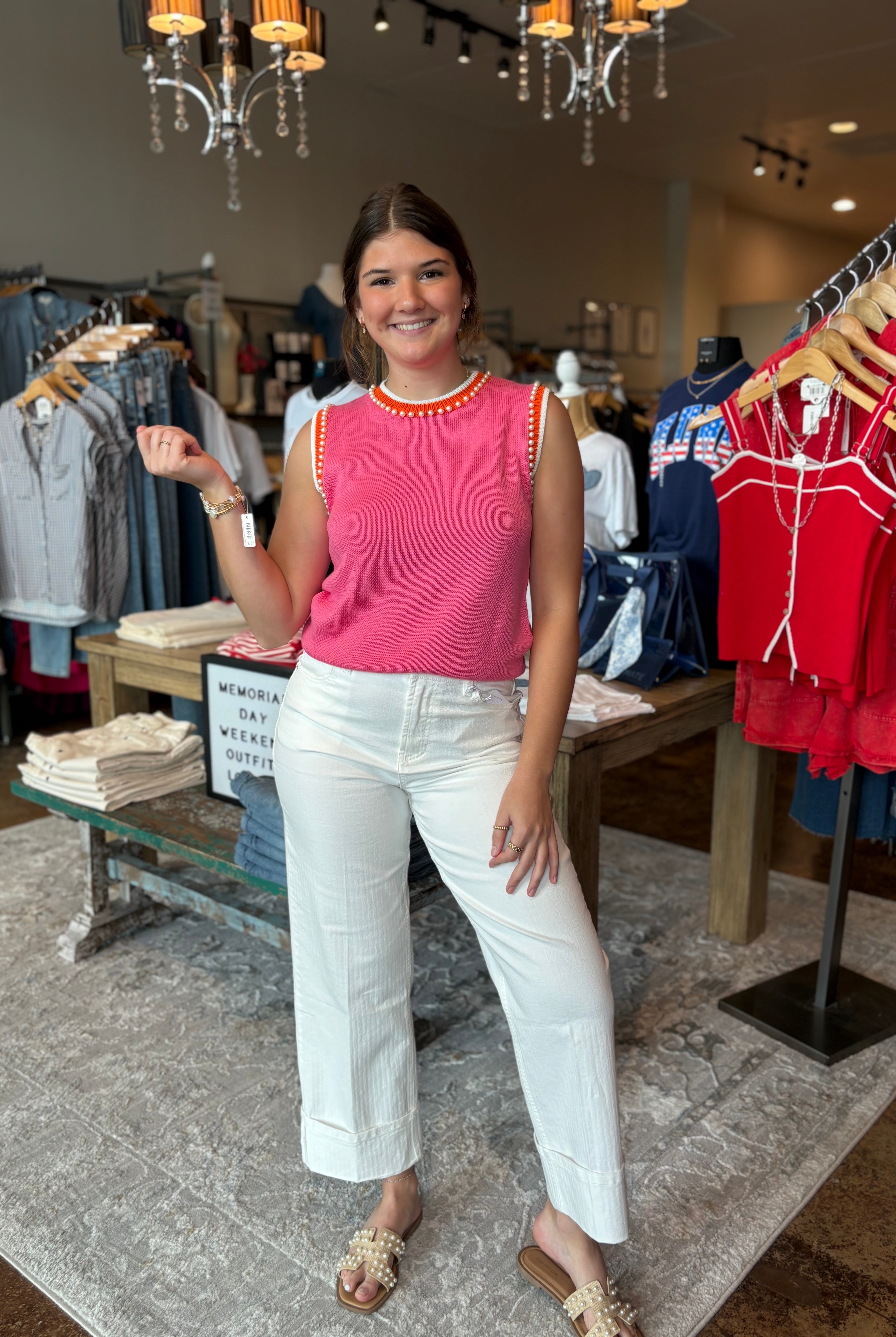 Woman in a pink top and white pants standing in a clothing store.