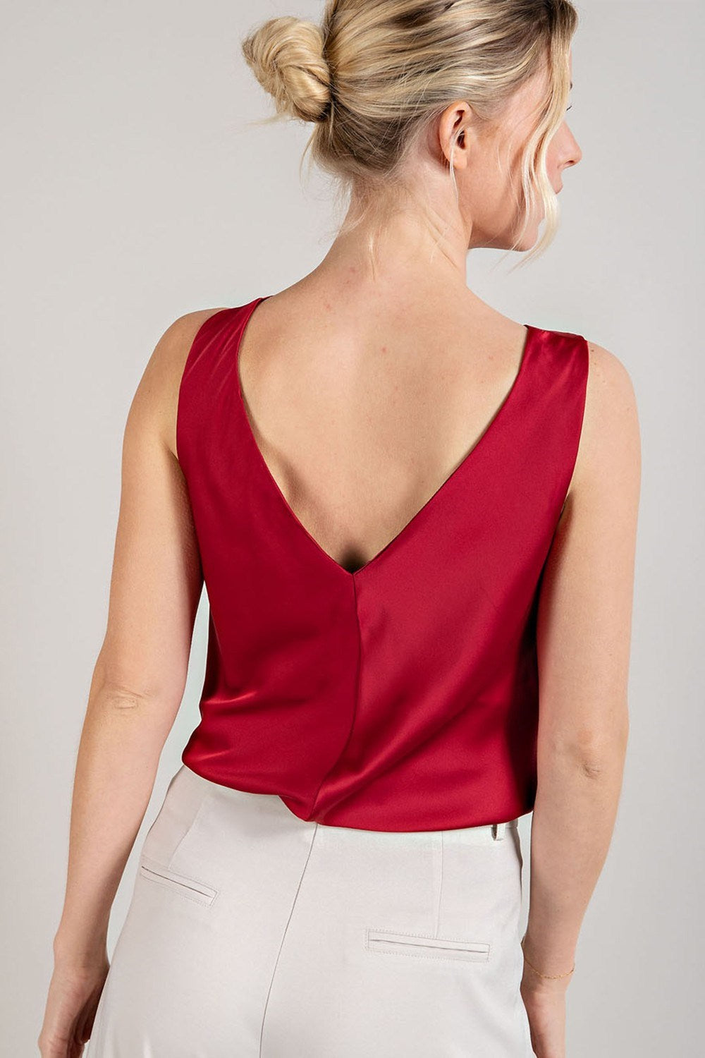 Woman wearing a red sleeveless top with a plain background
