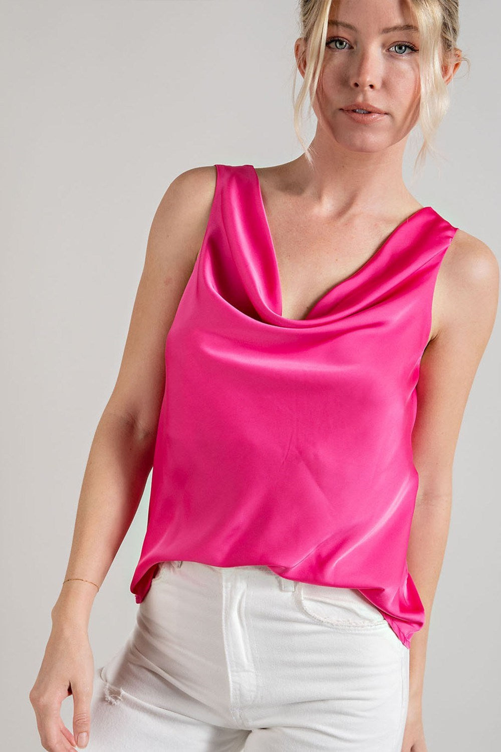Woman wearing a bright pink satin top against a plain background
