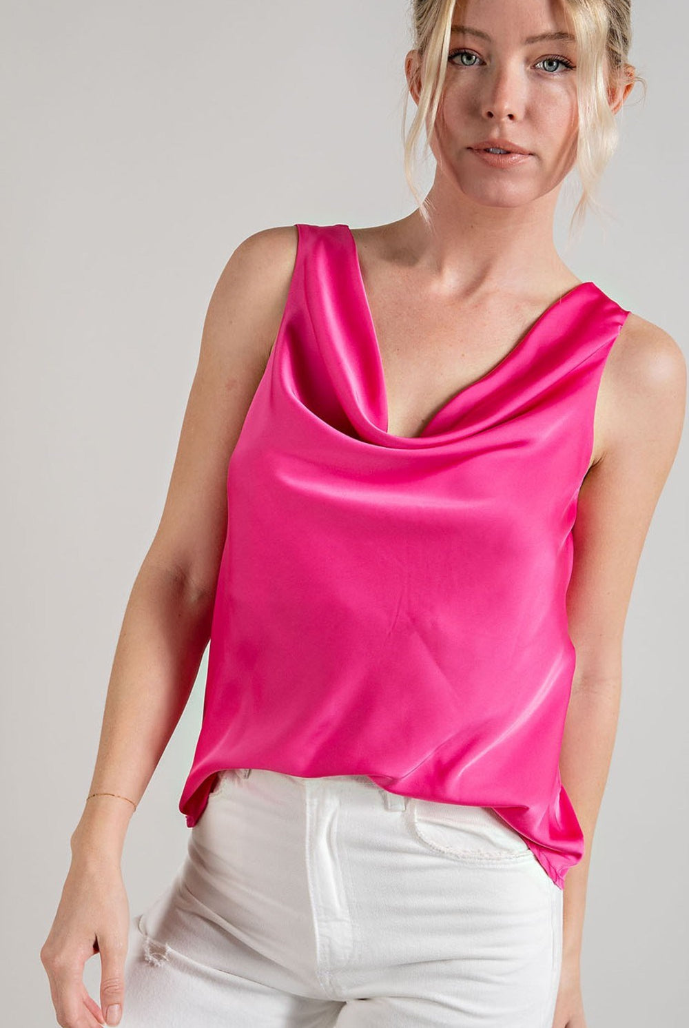 Woman wearing a bright pink satin top against a plain background