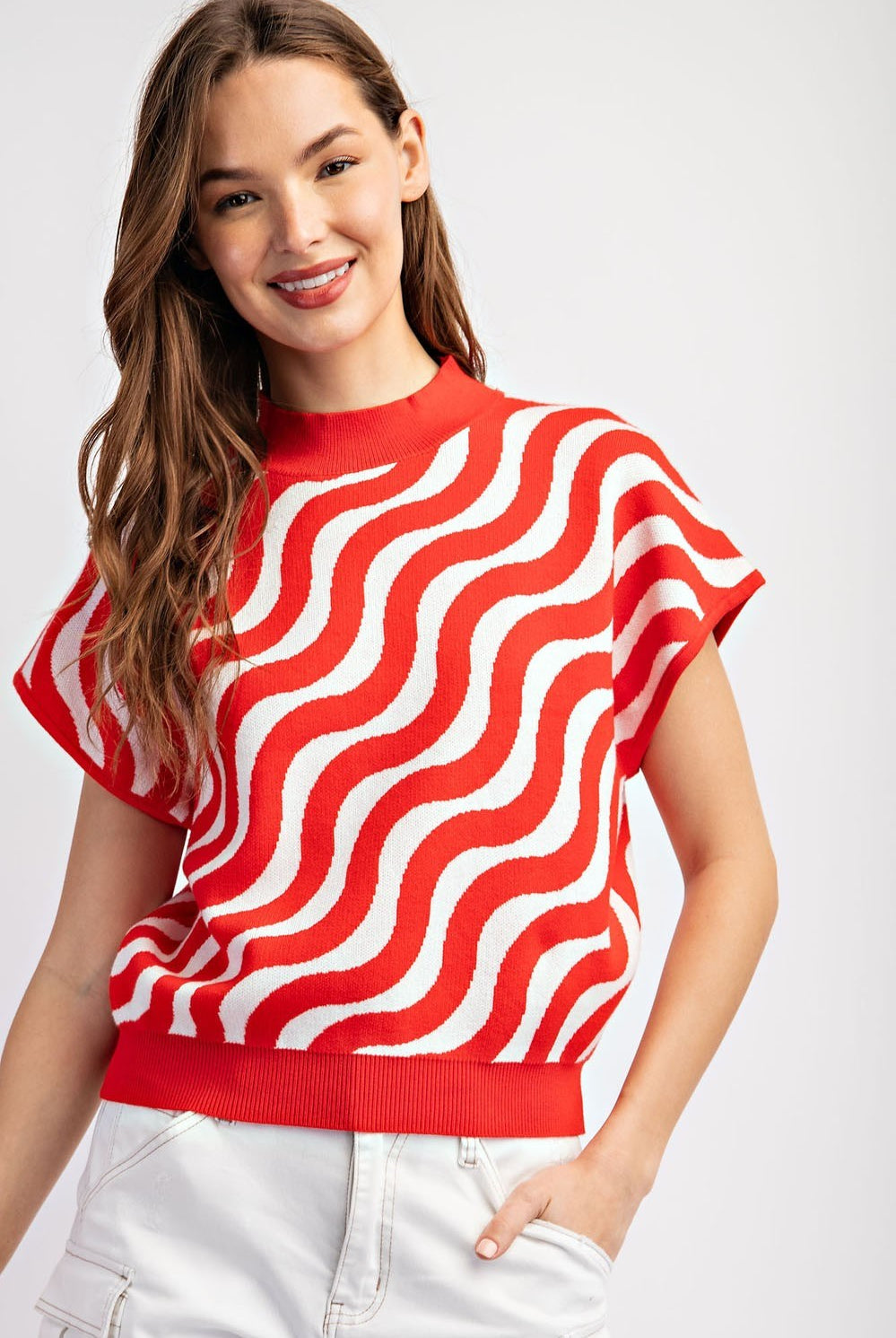 Woman wearing a red and white wavy patterned top on a white background