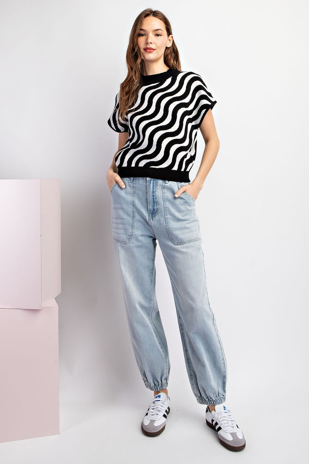 Woman wearing a black and white striped sweater and light blue jeans on a white background