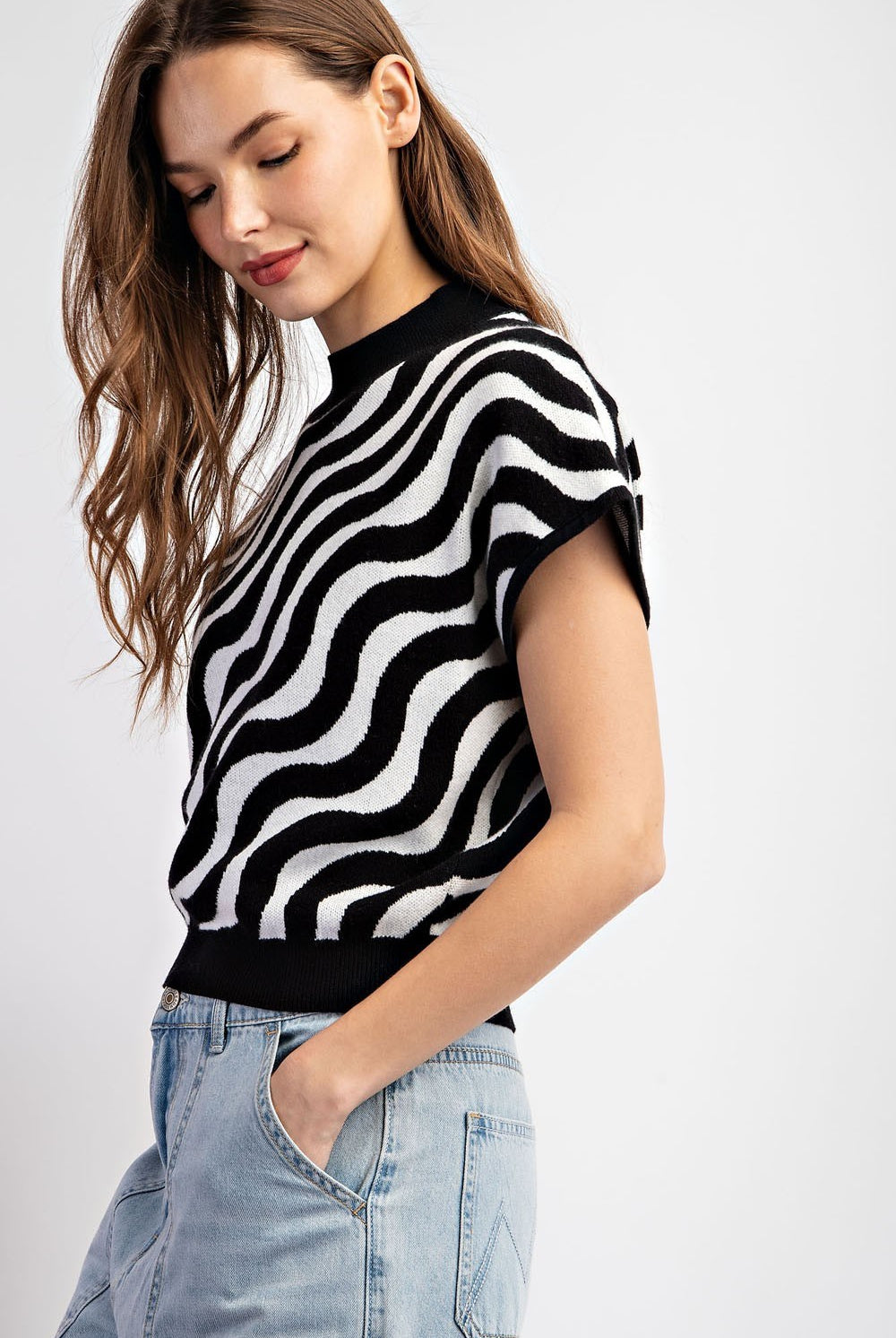 Woman wearing a black and white striped sweater with light blue jeans on a white background