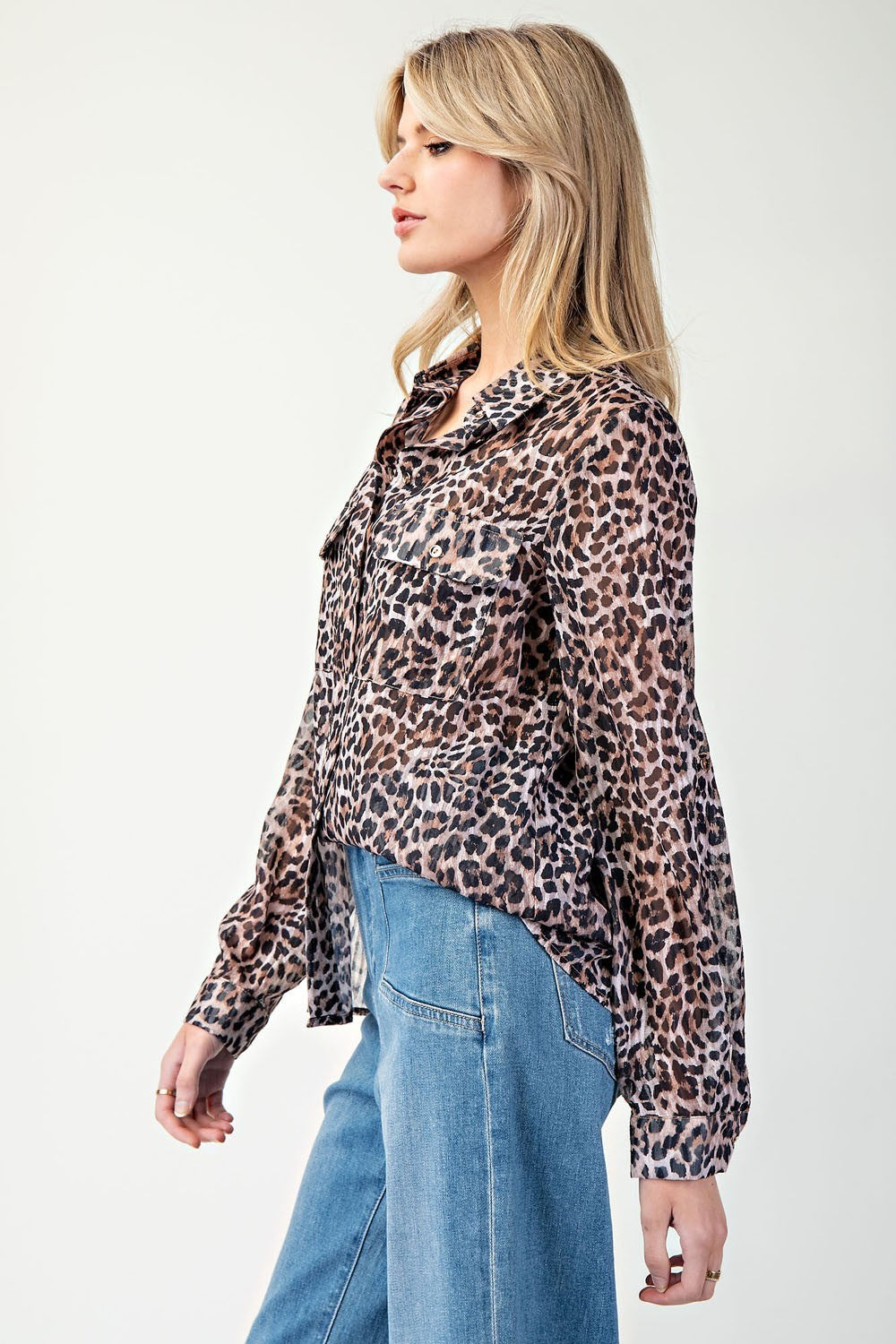 Woman wearing a leopard print shirt and blue jeans on a white background