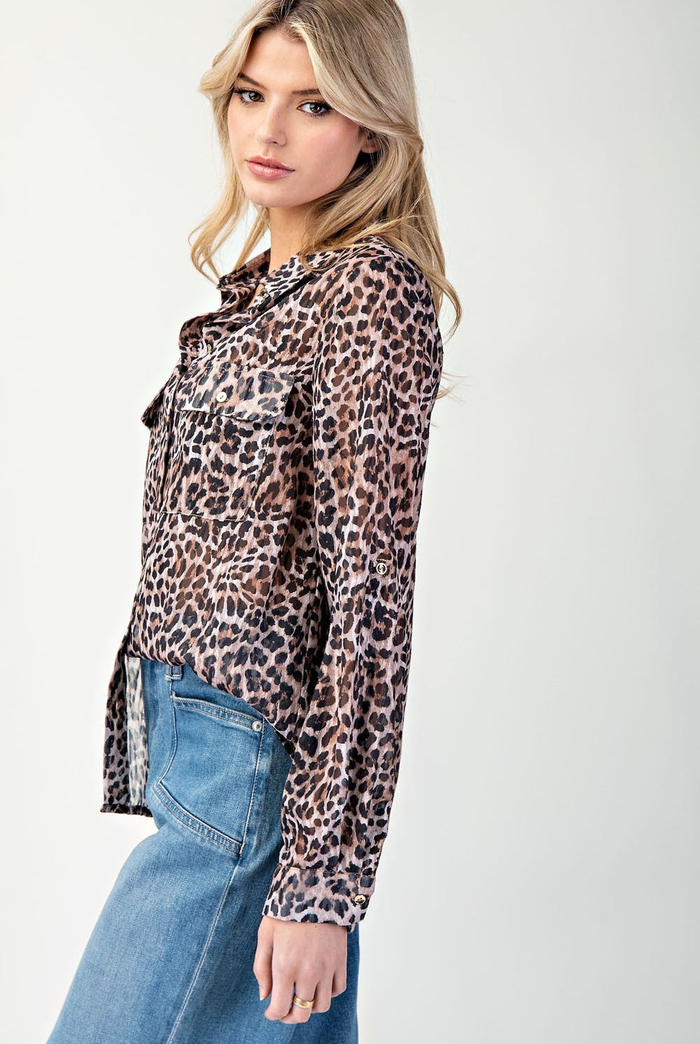 Woman wearing a leopard print shirt and blue jeans on a white background