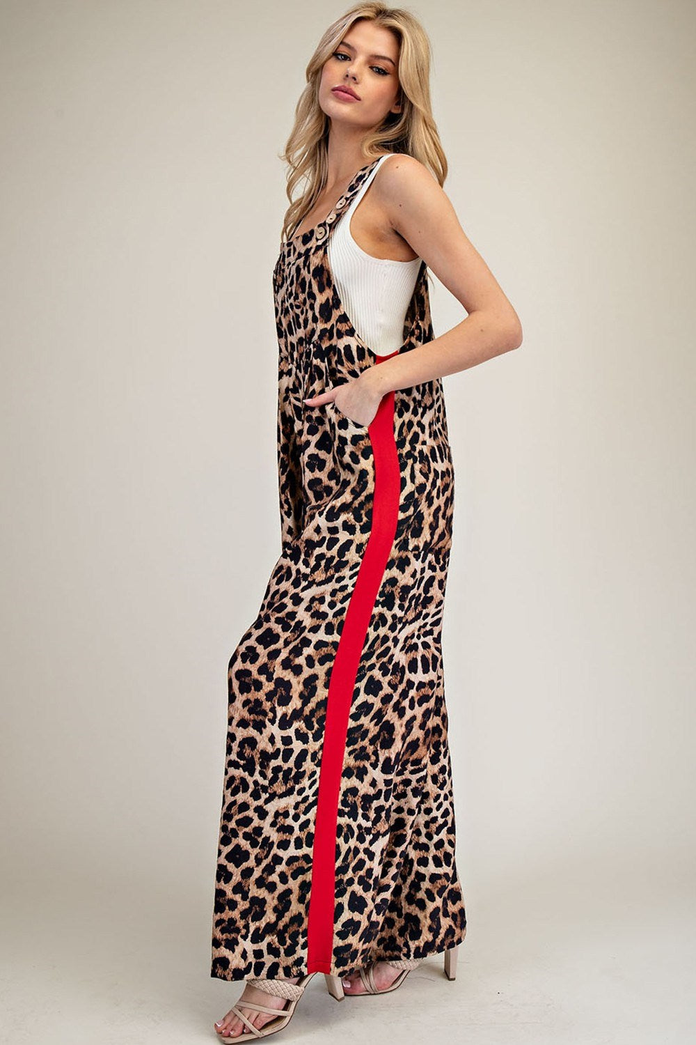 Woman wearing a leopard print dress with a red stripe on a plain background