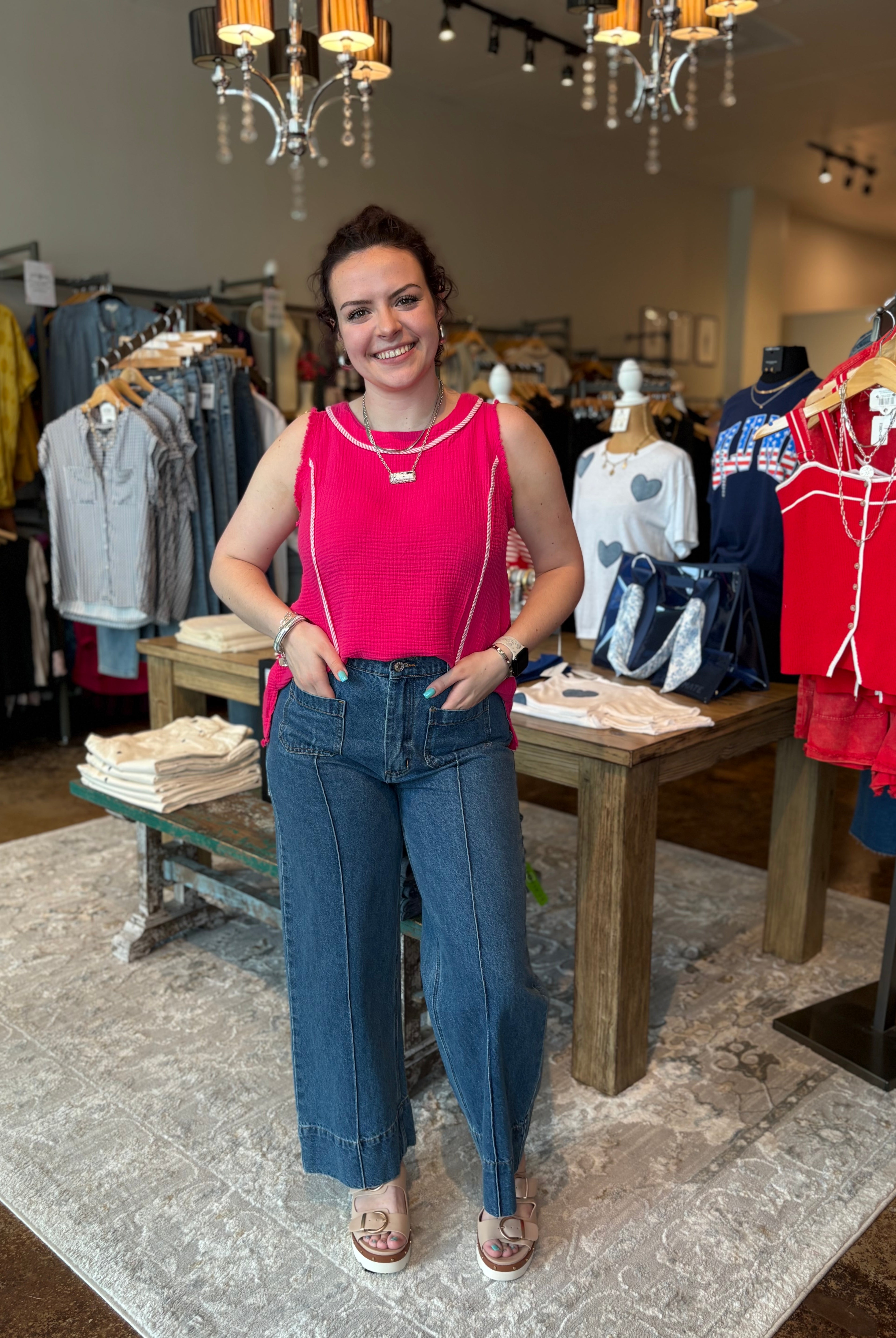 Woman in a pink top and blue jeans standing in a clothing store.