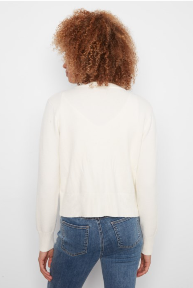 A woman with curly brown hair is shown from behind wearing a cream-colored knit sweater and blue jeans against a plain white background.