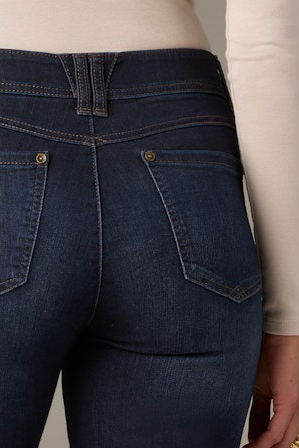 Close-up of dark blue jeans with a beige background