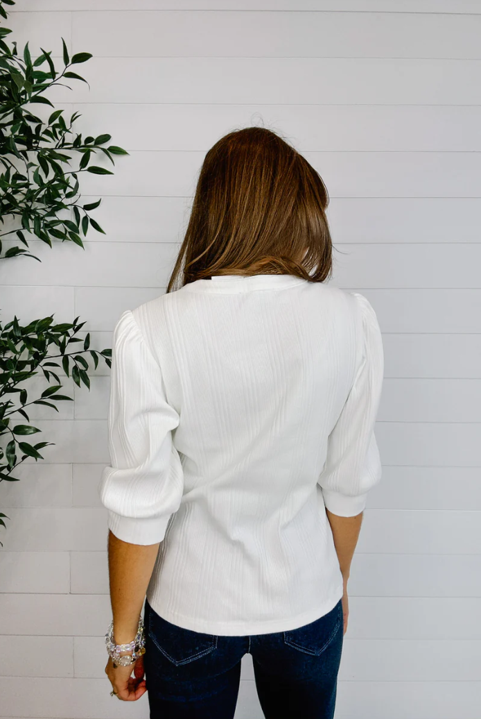 Woman wearing a white blouse with a plant on the left side of the frame