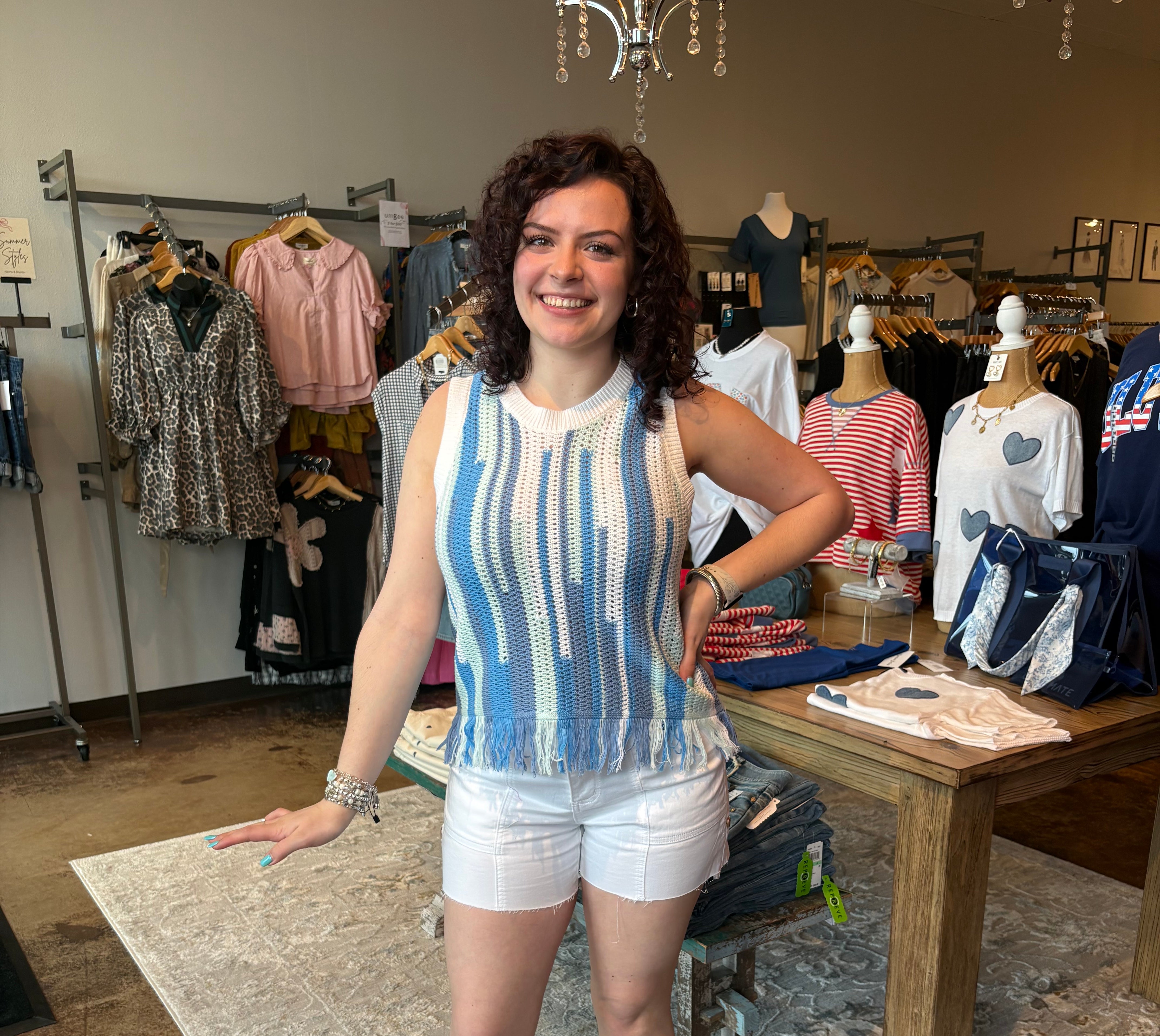 Woman wearing a crocheted sleeveless top. Blue and light green stripes on the tank