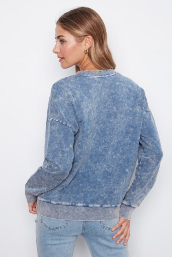 A woman shown from the back wearing a blue acid-wash crewneck sweatshirt and light-wash jeans against a plain white background.