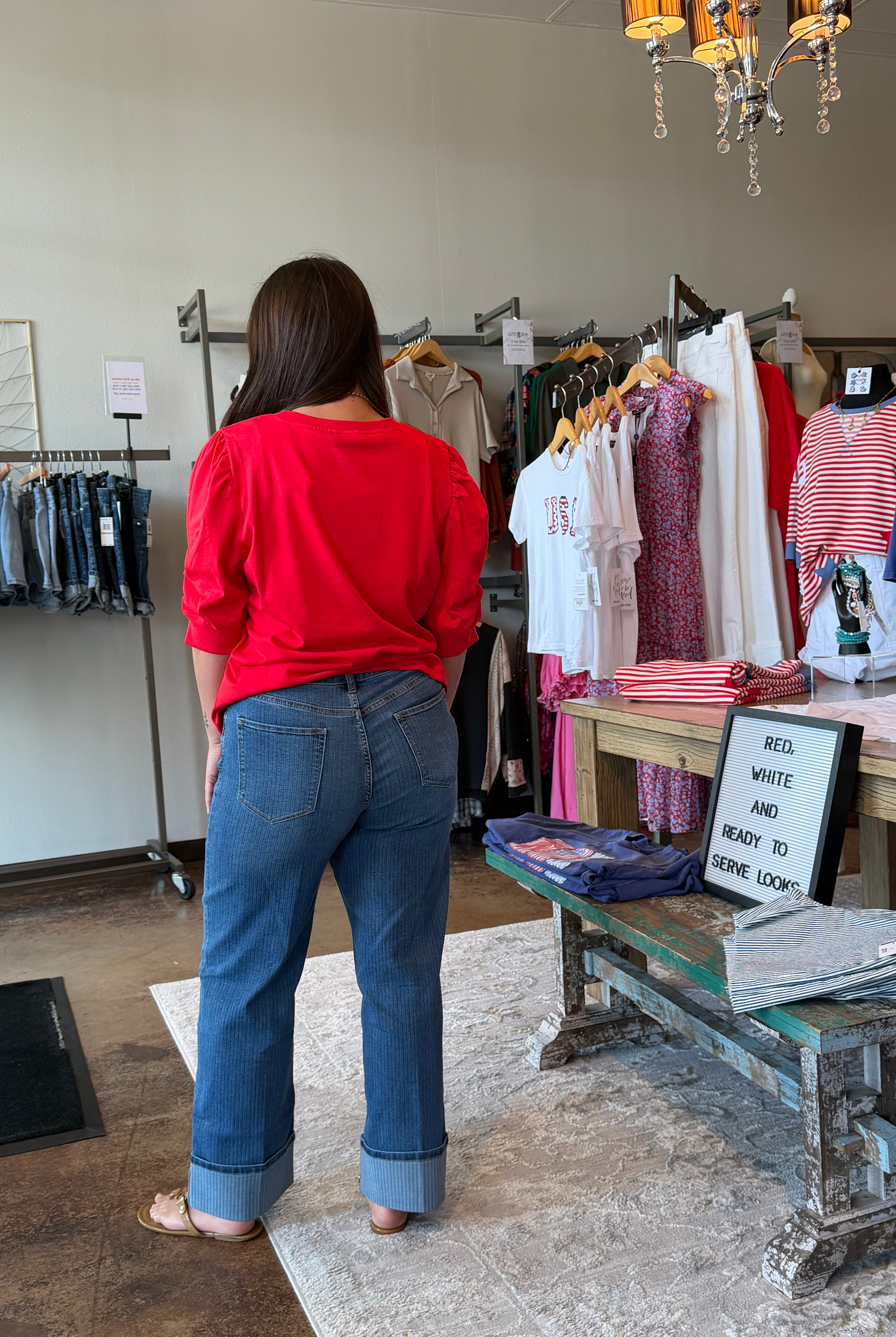 Person wearing a red shirt and blue jeans standing in a clothing store.