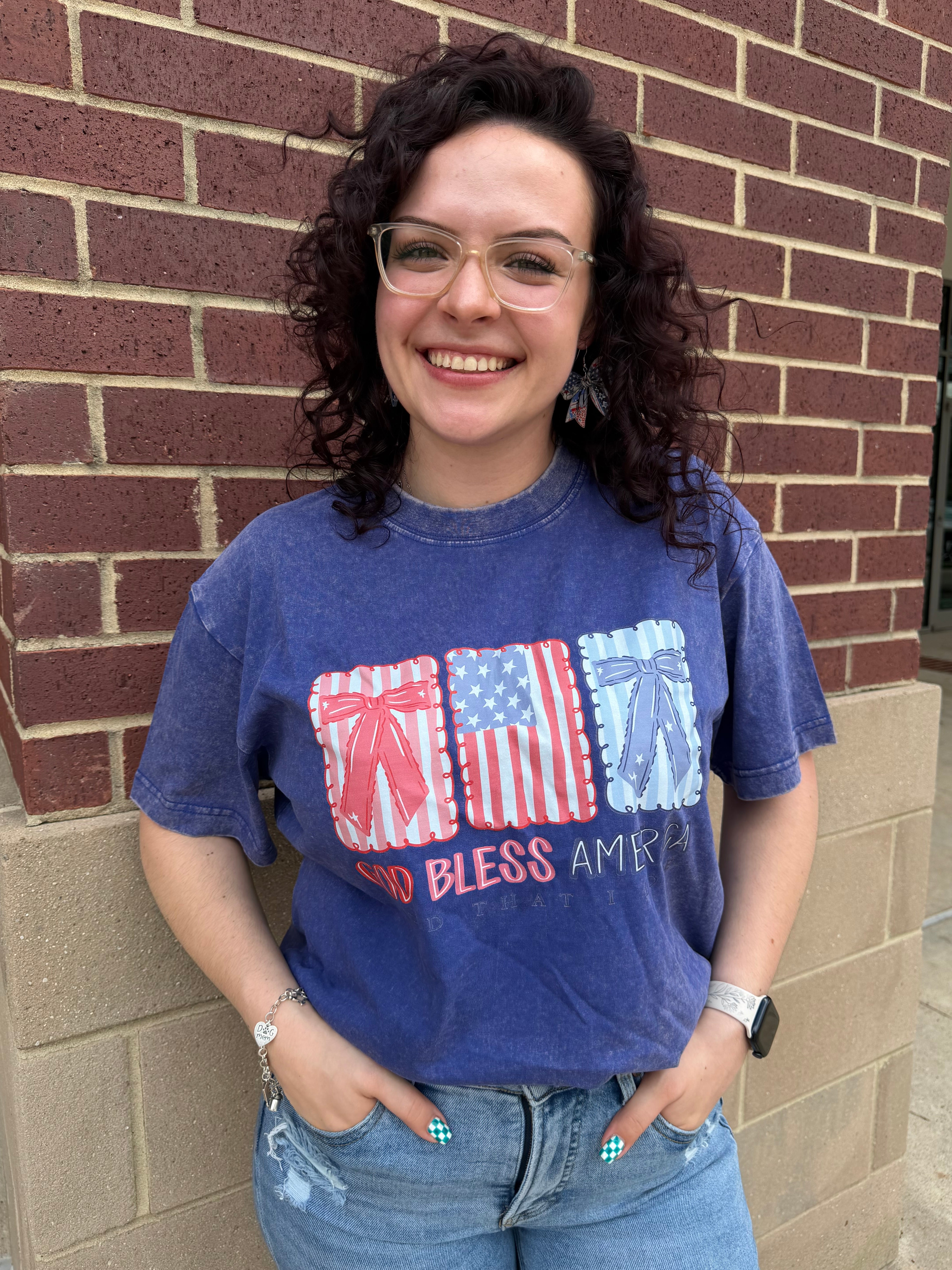 Person wearing a blue t-shirt with a graphic design standing against a brick wall.