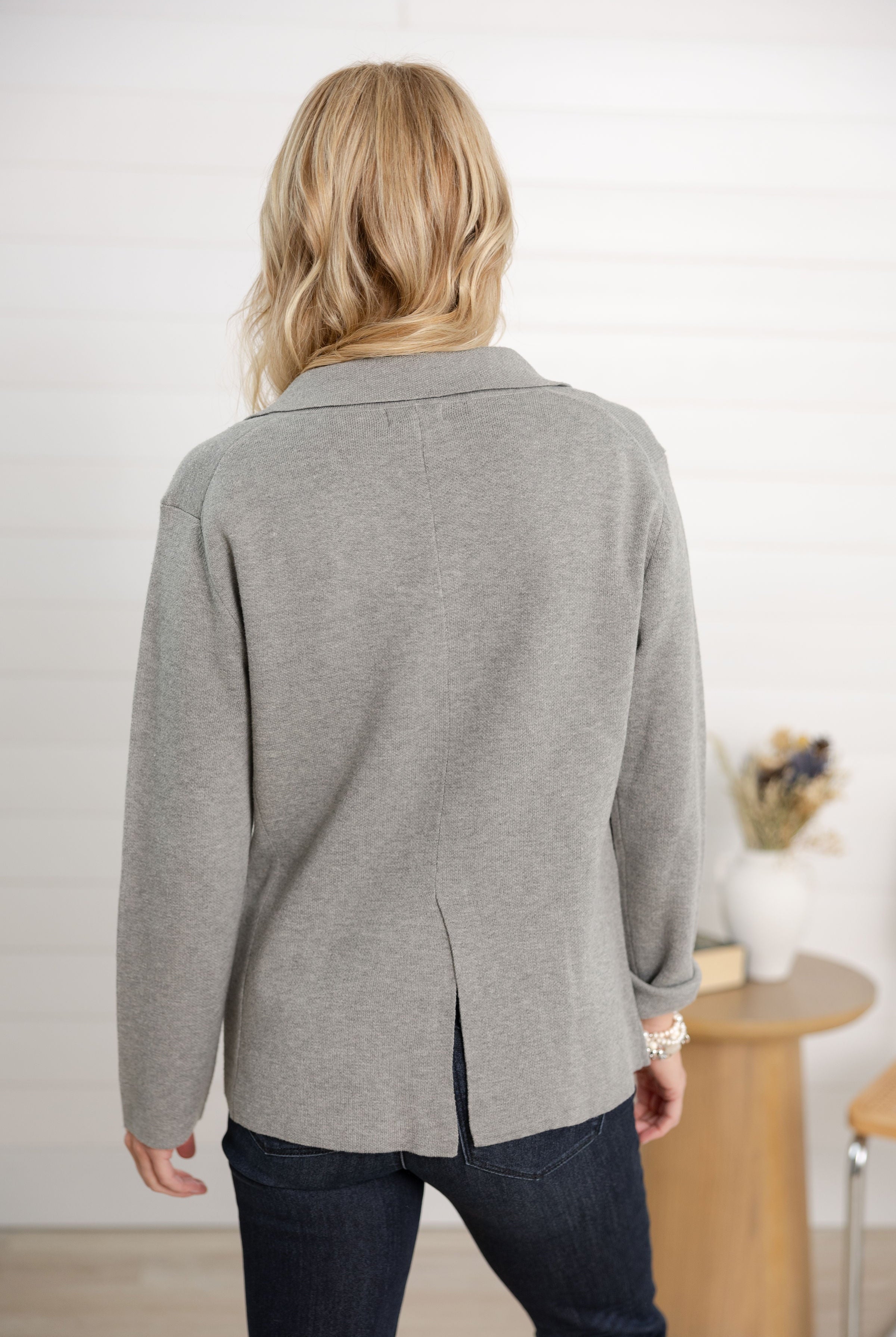 Person wearing a gray cardigan in an indoor setting
