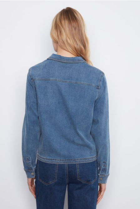 A woman viewed from the back wearing a medium-wash blue denim jacket over a dark blue denim shirt, set against a plain white studio background.