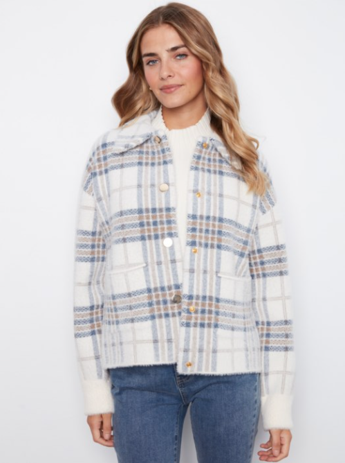 A woman wearing a white fuzzy plaid jacket with blue and tan stripes, paired with a white top and blue jeans, against a plain white background.