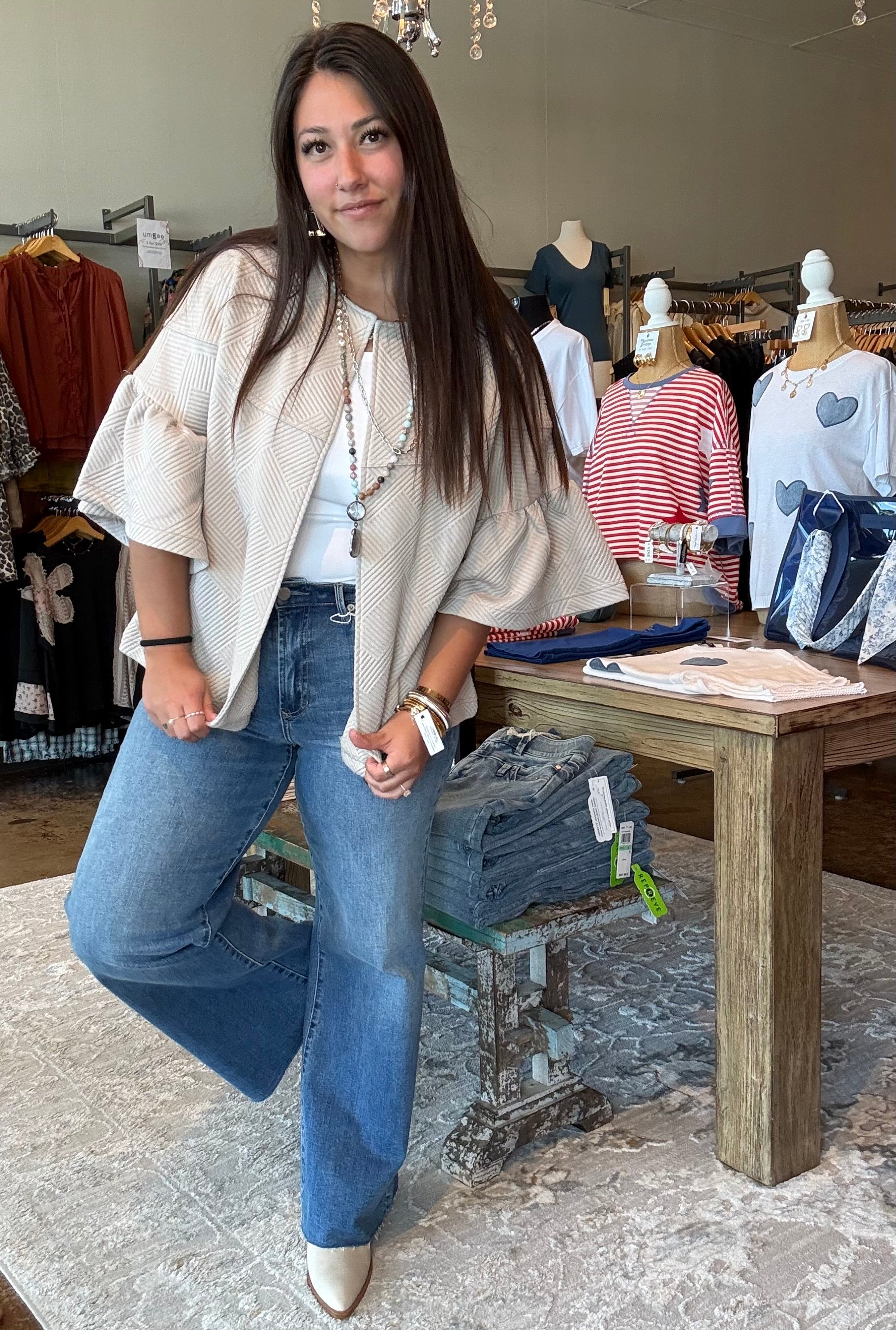 Woman posing in a clothing store with mannequins and clothing in the background