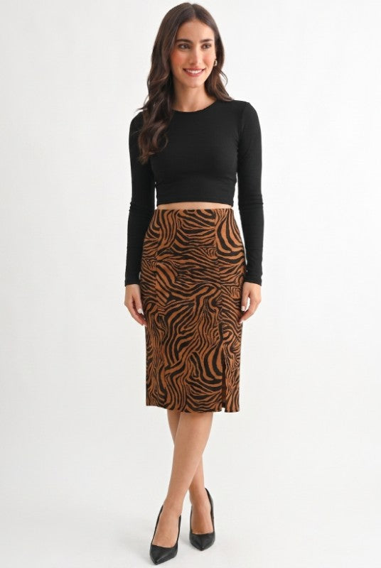 A woman modeling a black long-sleeve crop top and a brown and black zebra-print pencil skirt, paired with black pointed-toe heels, against a plain white studio background.