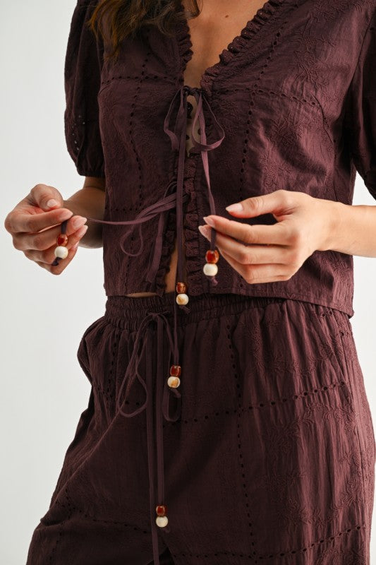Close-up of brown embroidered top tie-front closure with decorative beaded ends
