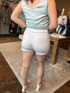 Person wearing a light blue sleeveless top and white shorts in a store setting.