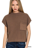 A woman wearing a brown short-sleeve ribbed knit top with a chest pocket, paired with blue jeans, against a plain white background.