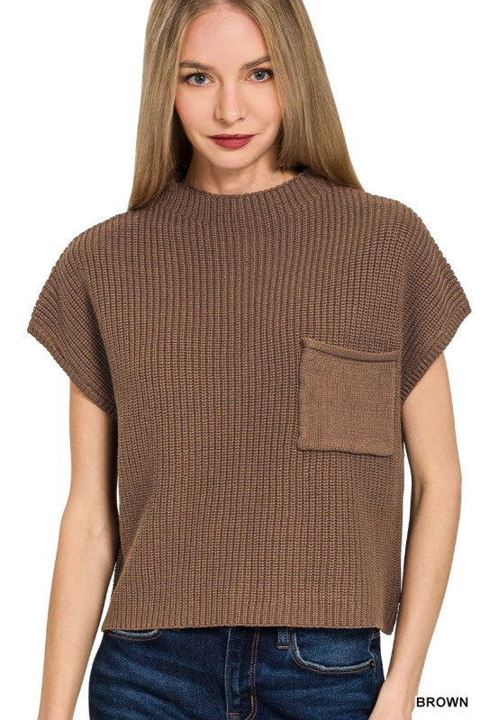 A woman wearing a brown short-sleeve ribbed knit top with a chest pocket, paired with blue jeans, against a plain white background.