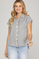 Woman wearing a black and white striped shirt with short sleeves on a gray background