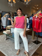 Woman in a pink top and white pants standing in a clothing store.