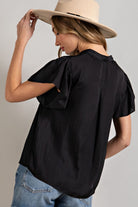 Woman wearing a black blouse and beige hat on a gray background