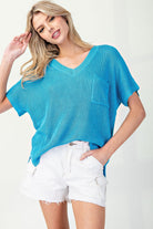 Woman wearing a blue sweater and white shorts on a plain background