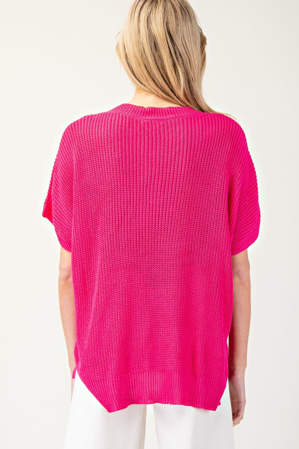 Person wearing a bright pink sweater on a white background