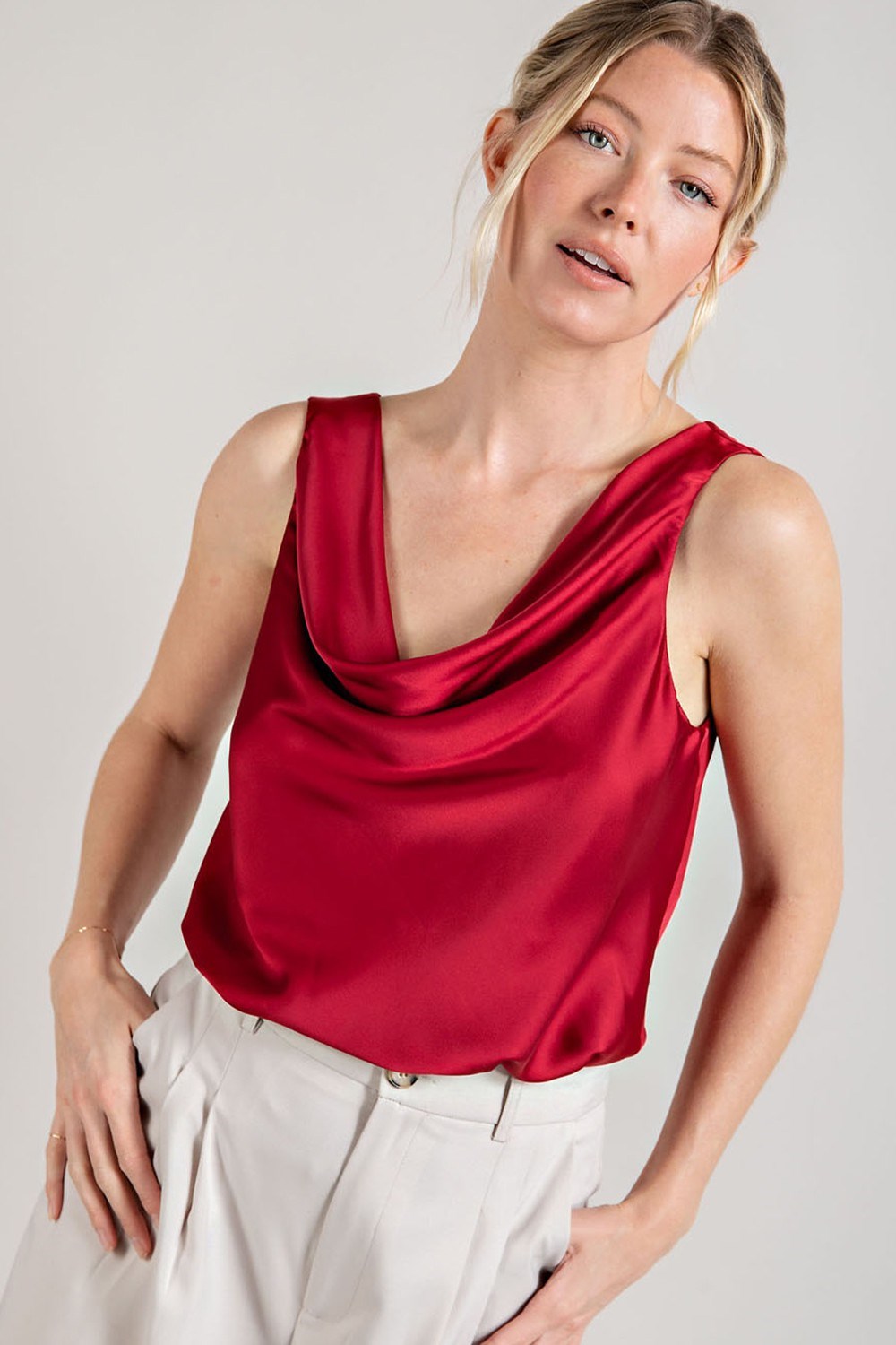 Woman wearing a red satin top against a plain background