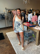 Woman standing in a clothing store wearing a sleeveless top and shorts.