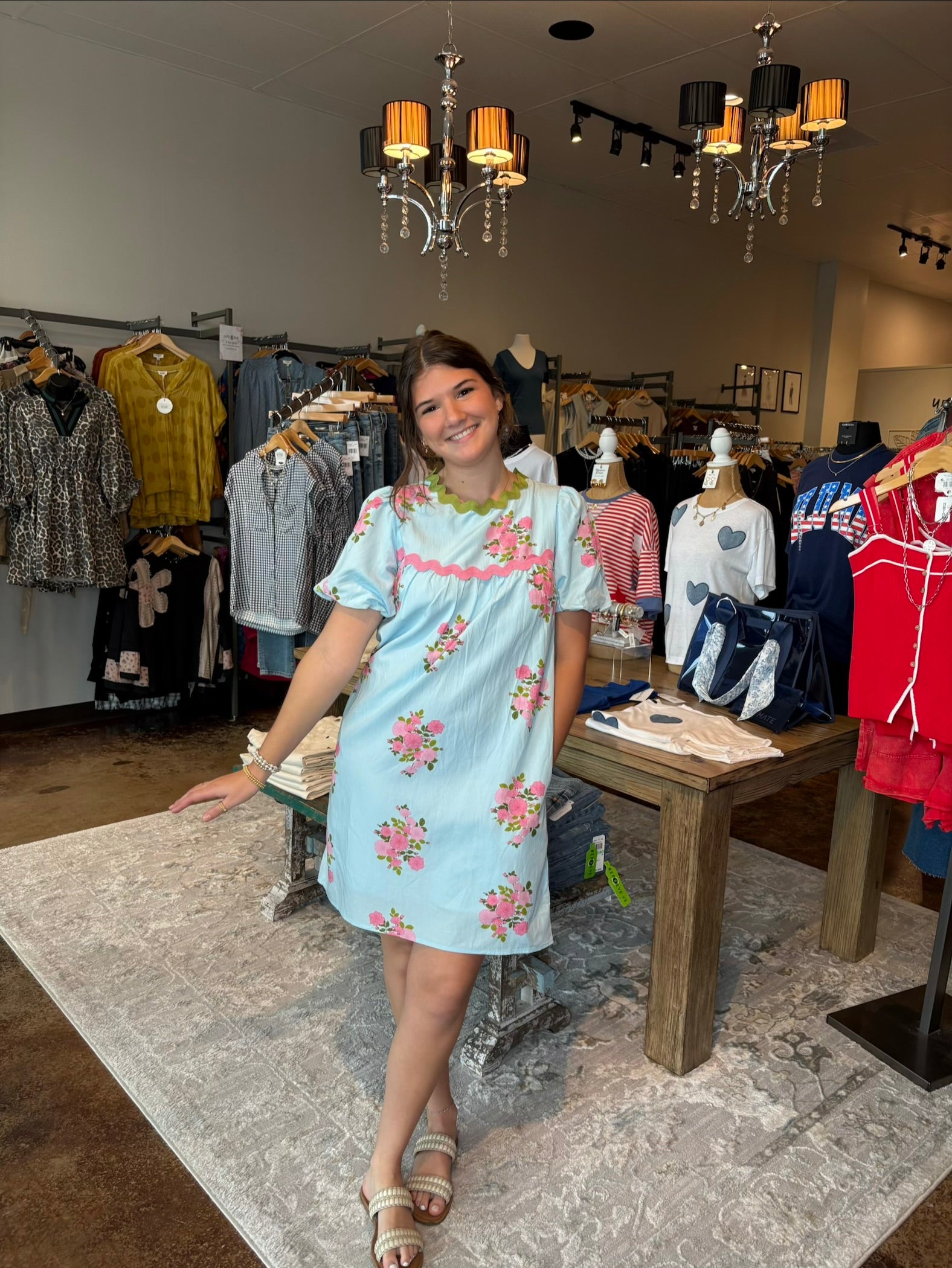 Young girl in a light blue floral dress standing in a clothing store.