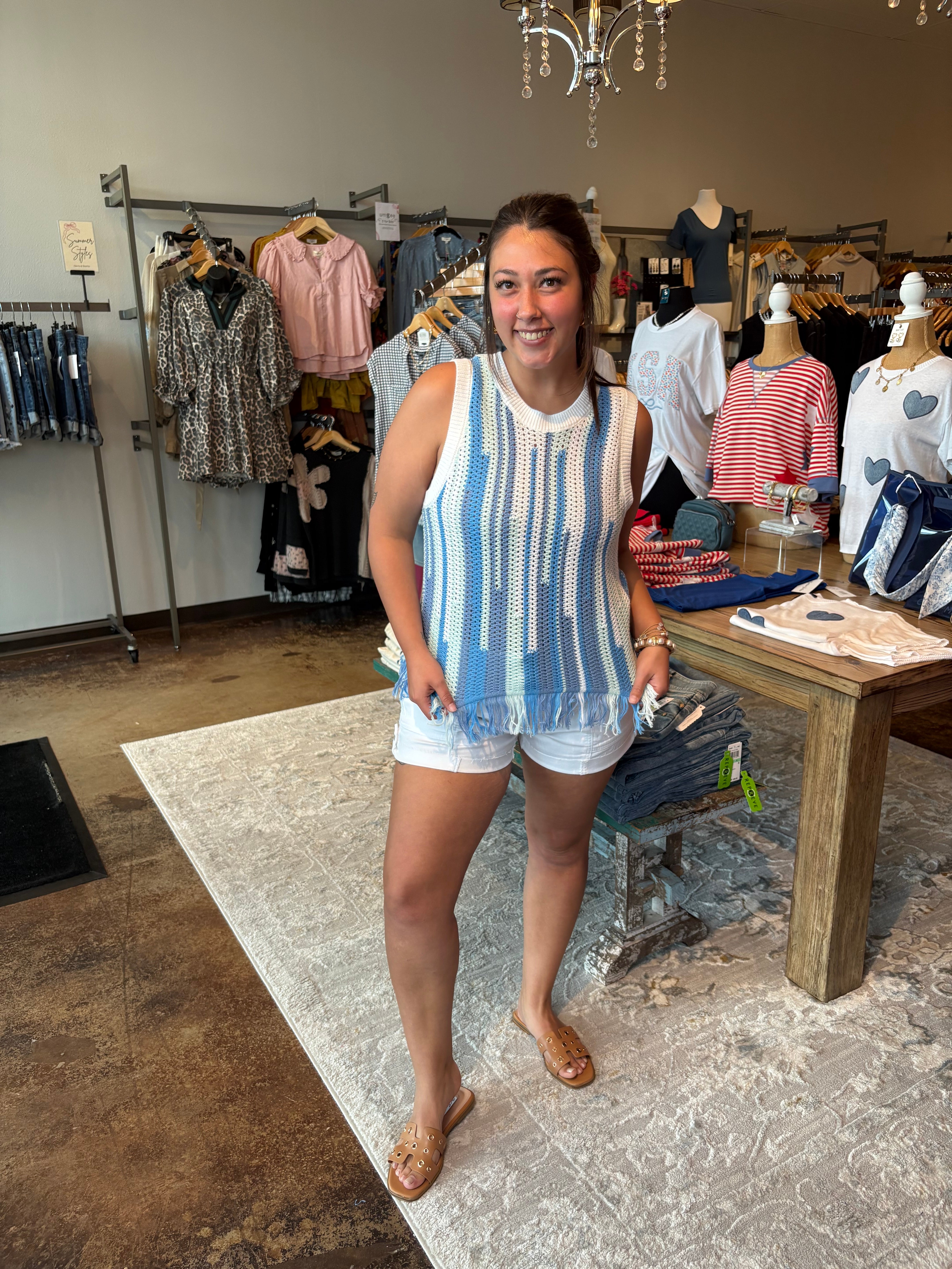 Woman in a striped tank top and shorts standing in a clothing store.