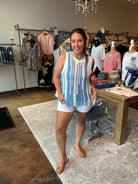 Woman in a striped tank top and shorts standing in a clothing store.