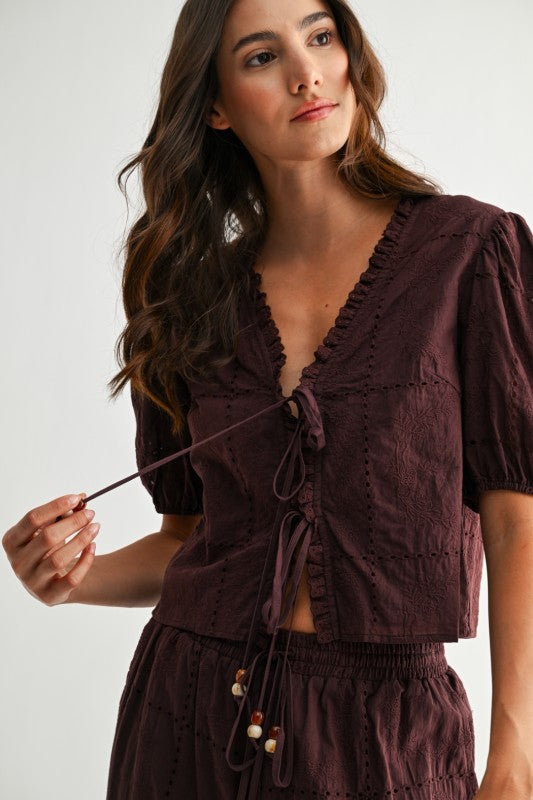 Model wearing brown embroidered puff sleeve tie-front top, close-up of neckline and tie detail