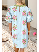 Light blue dress with pink floral patterns worn by a person, standing on pebbles.