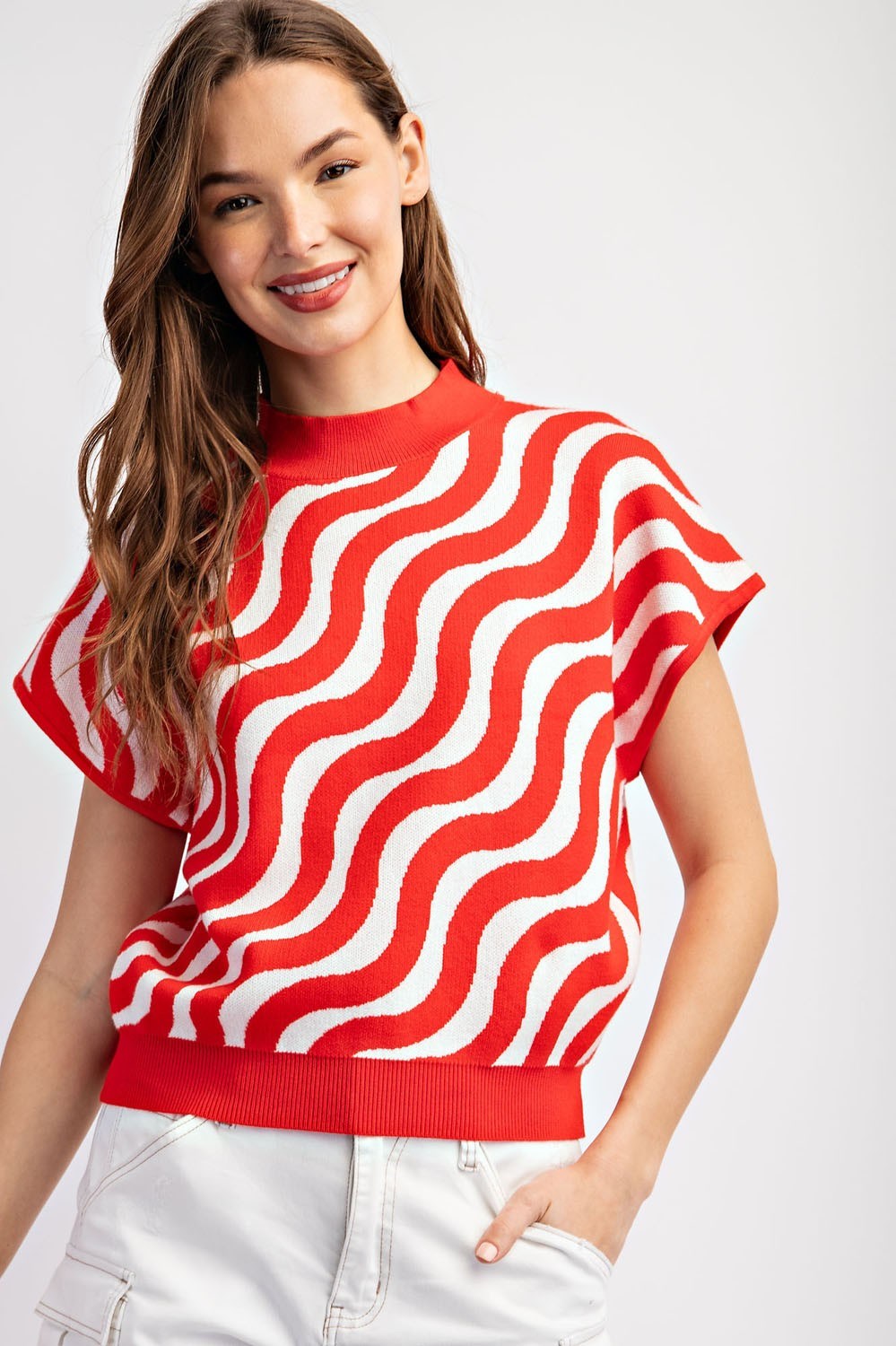 Woman wearing a red and white wavy patterned top on a white background