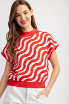 Woman wearing a red and white wavy patterned top on a white background