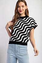Woman wearing a black and white striped sweater with light blue jeans on a plain background