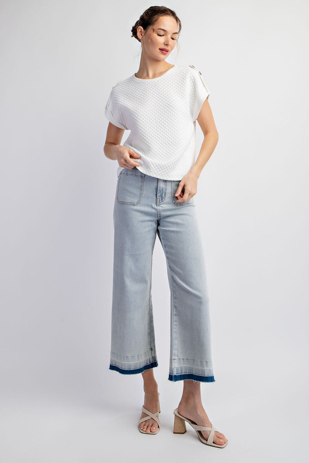 Woman wearing a white top and light blue jeans on a white background