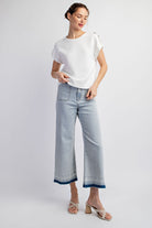 Woman wearing a white top and light blue jeans on a white background